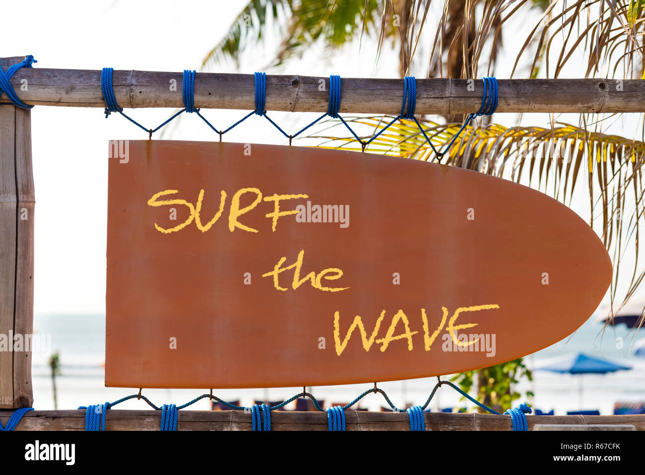Orange vintage Schild in Form von Surfbrett mit Surf Wave Text und Palmen im Hintergrund Stockfoto