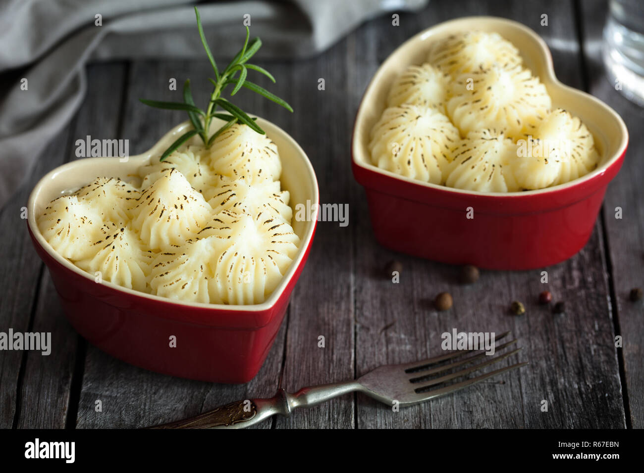 Shepherd's Pie in kleinen, individuellen Herzform rot ramikens, traditionelle britische Gerichte mit Hackfleisch und Kartoffelbrei auf rustikalen Holztisch Stockfoto