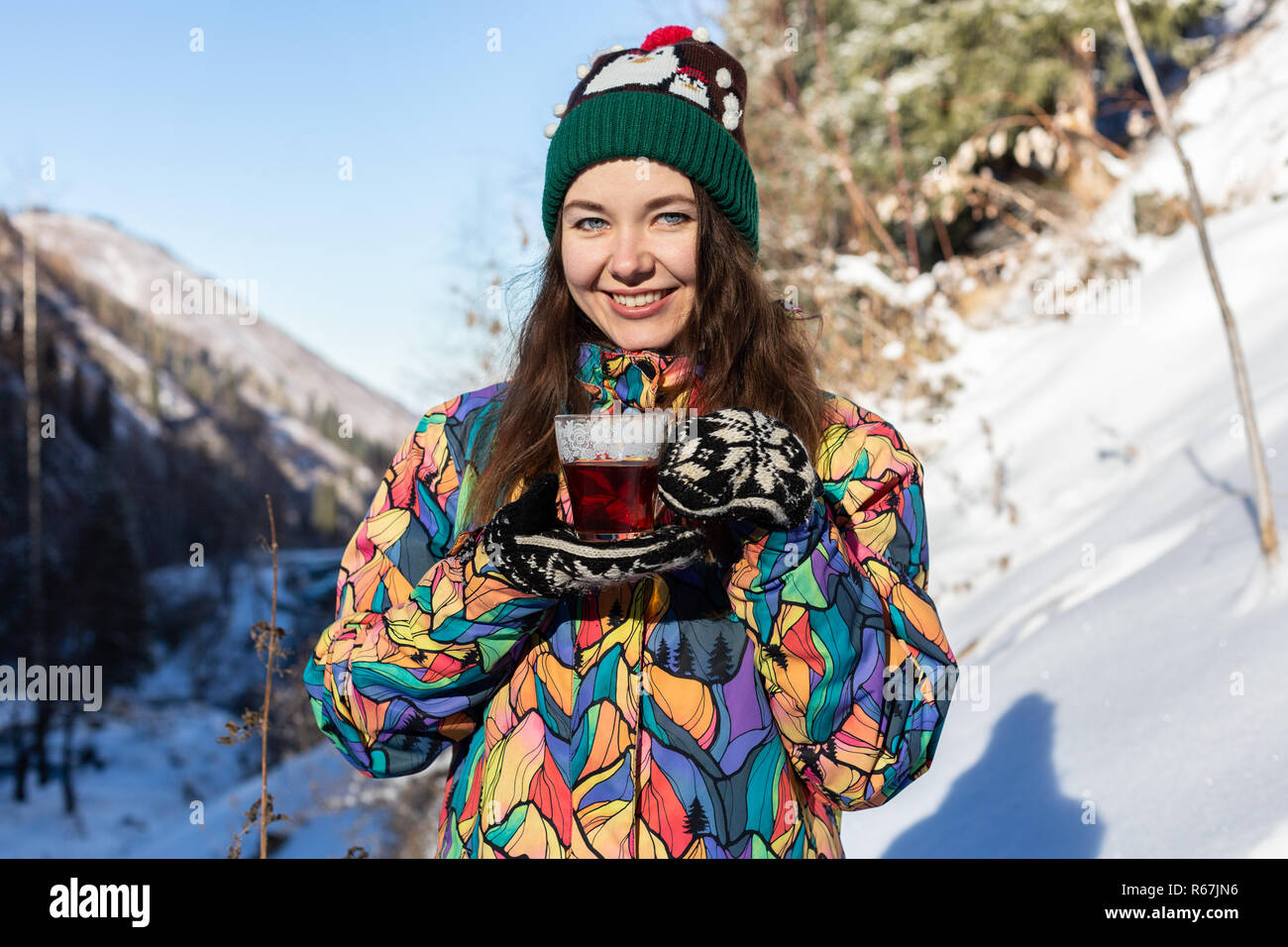 Mädchen genießt den Schnee fällt. Junge Frau in Form gestrickt ist Tee trinken im Wald bei einem Schneefall. Getönten Foto. Stockfoto