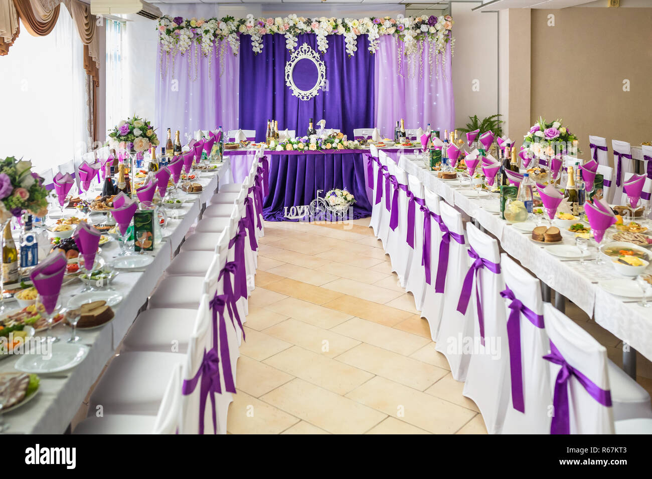Wunderschöne Blumen auf elegante Tisch in der Hochzeitstag. Dekorationen diente auf dem festlichen Tisch in der violetten Hintergrund Stockfoto