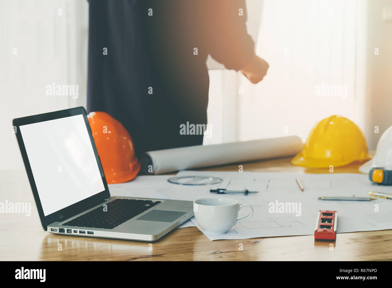 Leere leerer Bildschirm Laptop mit einer Tasse Kaffee und Blueprint von hölzernen Tisch in Office mit dem Architekten Hintergrund Stockfoto