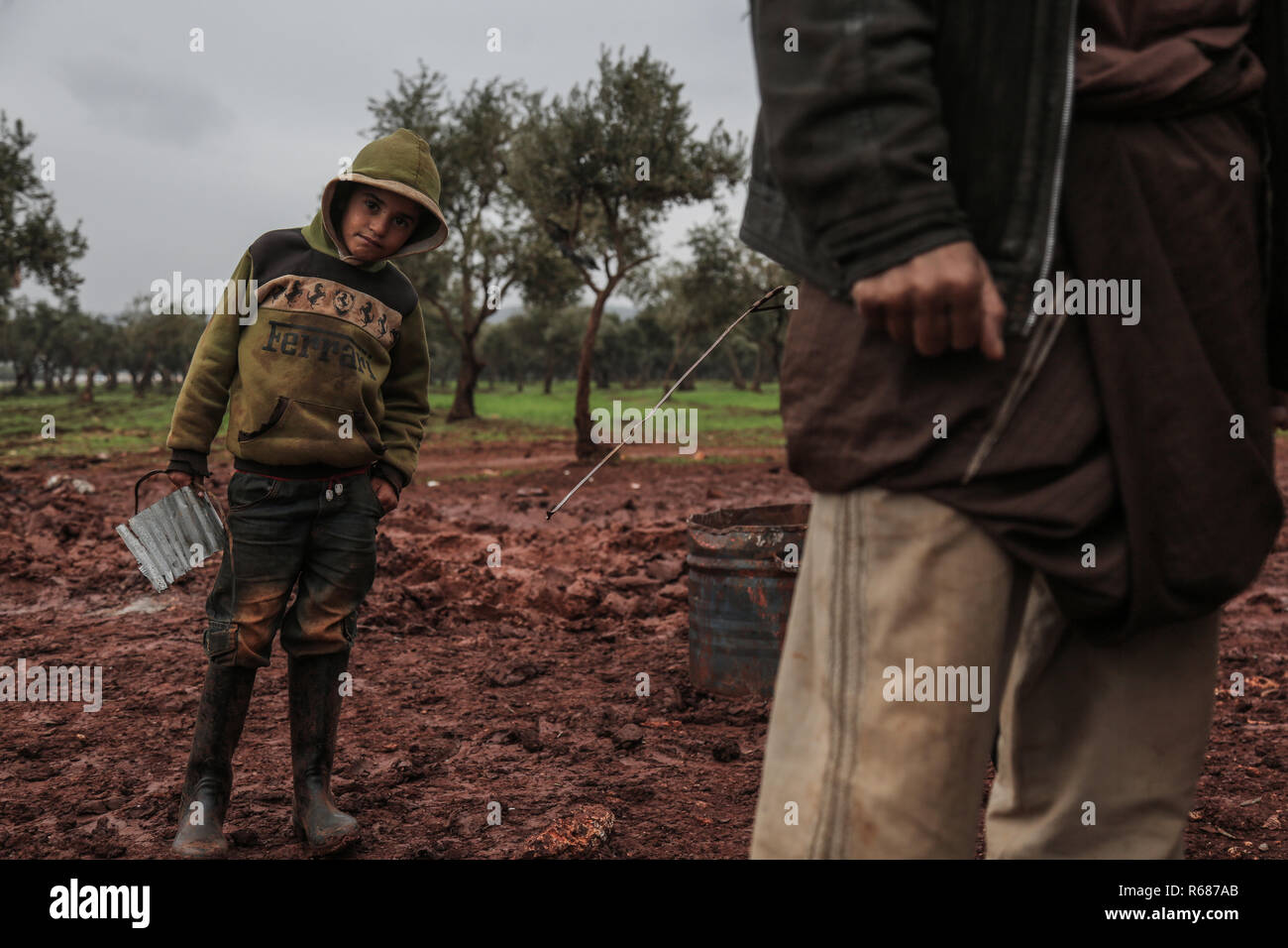 Idlib, Syrien. 04 Dez, 2018. Vertriebene syrischen Jungen stand im Schlamm bei Regenwetter an einem Lager für Vertriebene in der Nähe der syrischen Grenze Syrian-Turkish im nördlichen Umland von Idlib. Credit: Anas Alkharboutli/dpa/Alamy leben Nachrichten Stockfoto