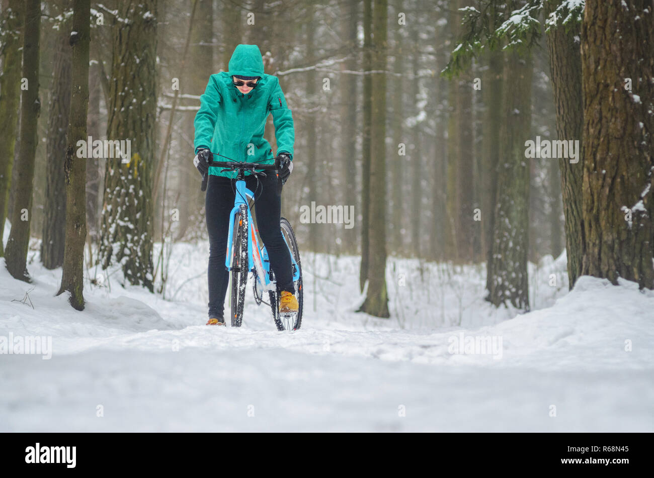 Radfahrer auf Cyclocross Bike Trails in den verschneiten Wald im Winter. Bergab auf einem schneebedeckten Hang. Winter Training im Freien Konzept Stockfoto