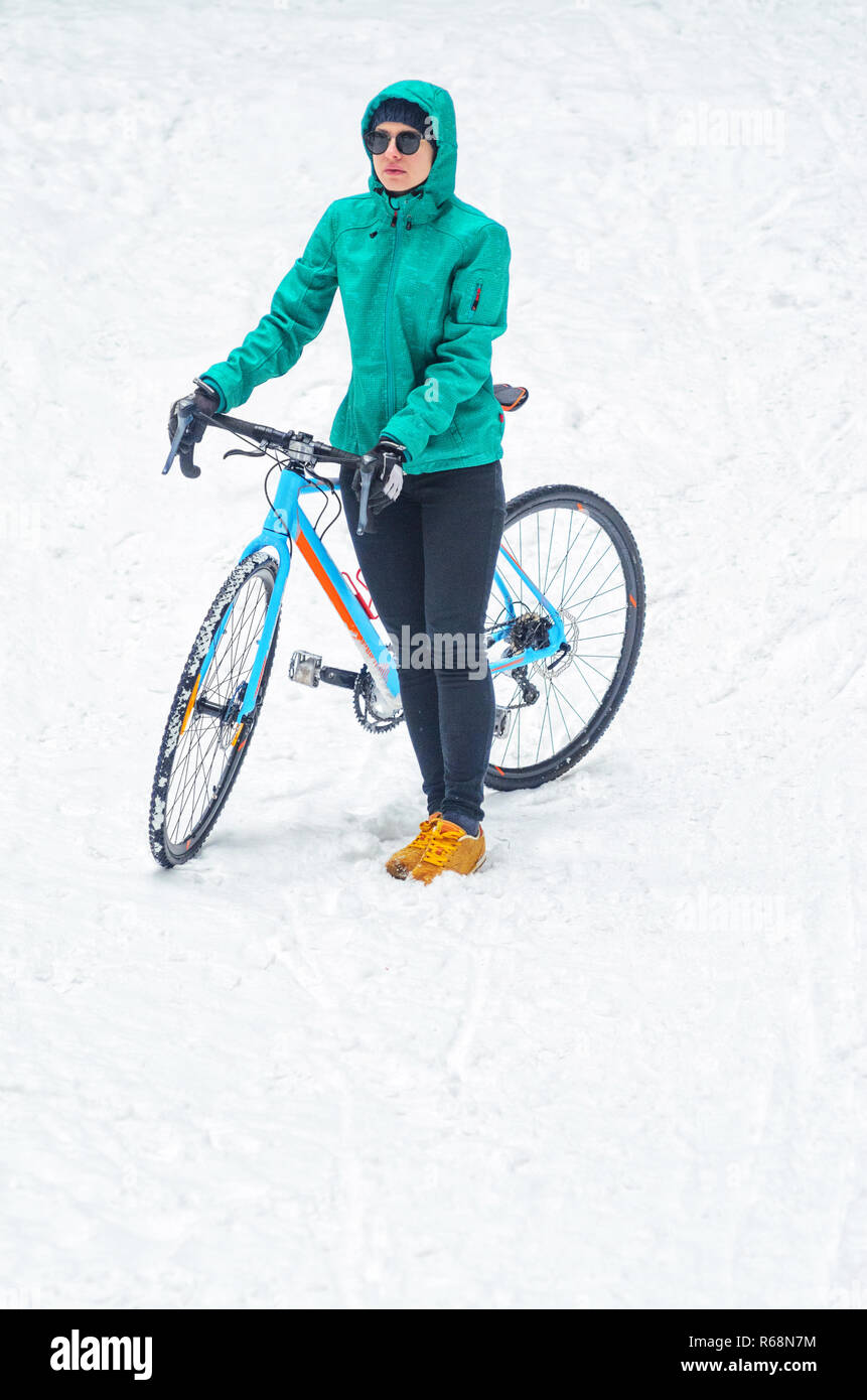 Radfahrer Frau steht in der Nähe von seinem Fahrrad. Radwege in den verschneiten Wald im Winter. Winter Training im Freien Konzept Stockfoto