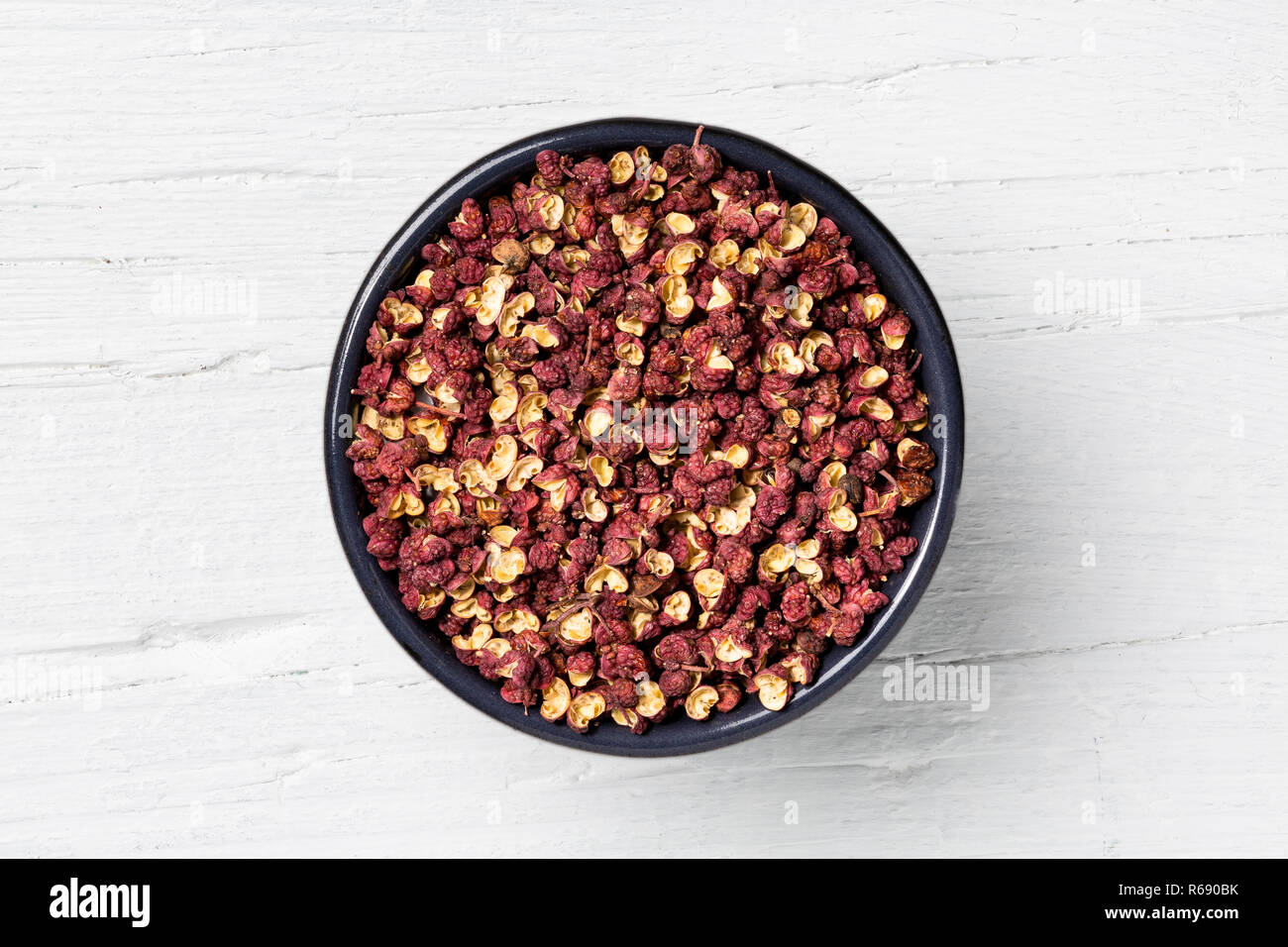 Szechuan Pfeffer aus Guss runde Tasse auf weißem Holz- Hintergrund, Blick direkt von oben. Stockfoto