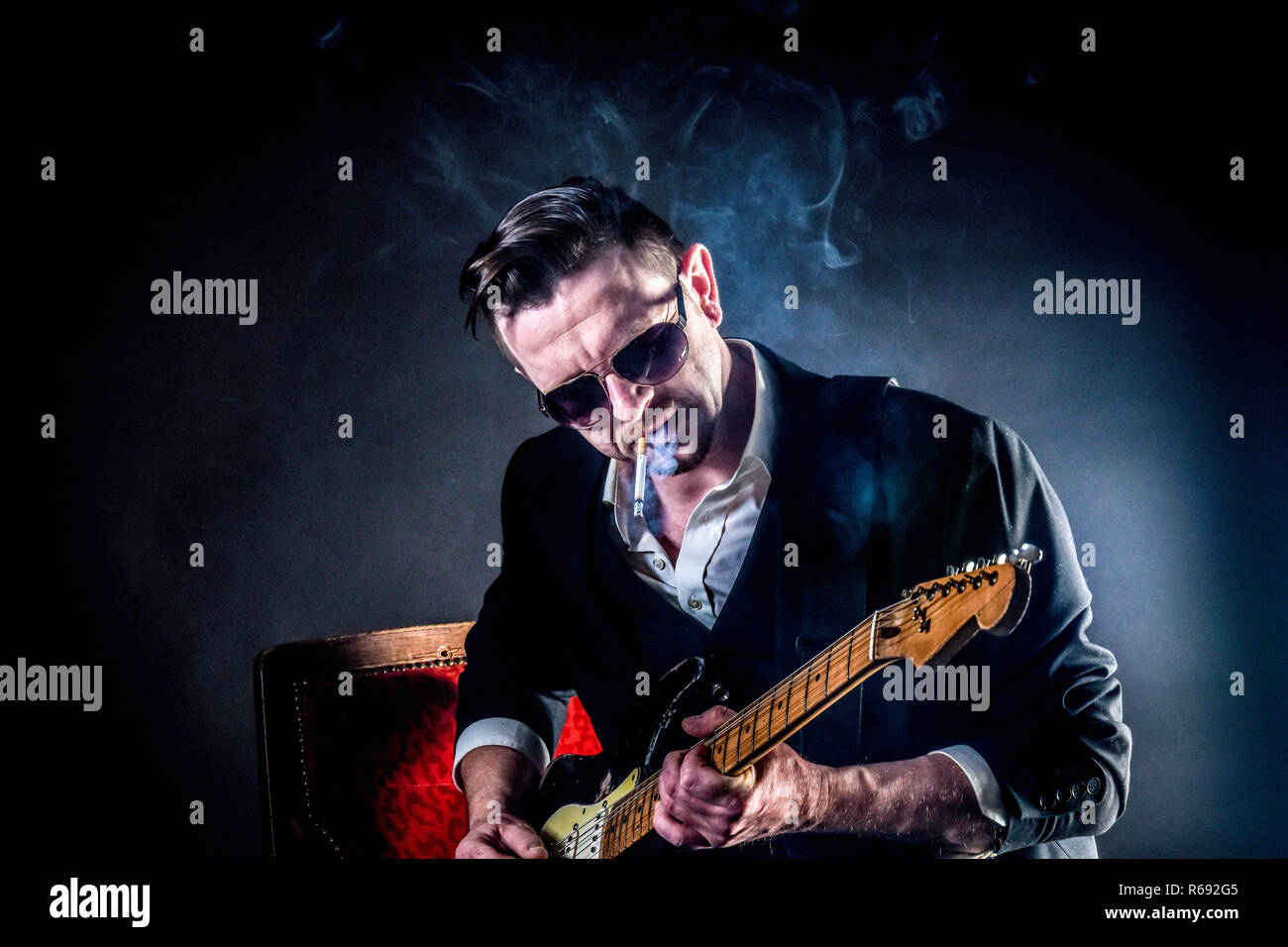 Coole Musiker spielt auf der Gitarre Ans raucht eine Zigarette  Stockfotografie