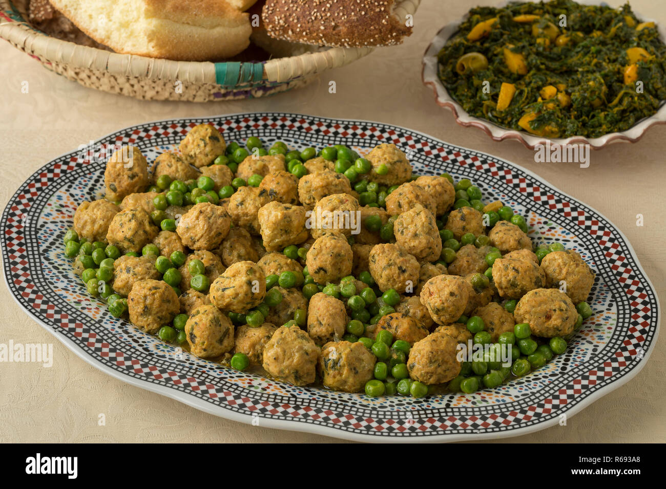 Schale mit marokkanischen Stil Hackfleisch Huhn Kugeln und grünen Erbsen, Spinat, Salat und Brot Stockfoto