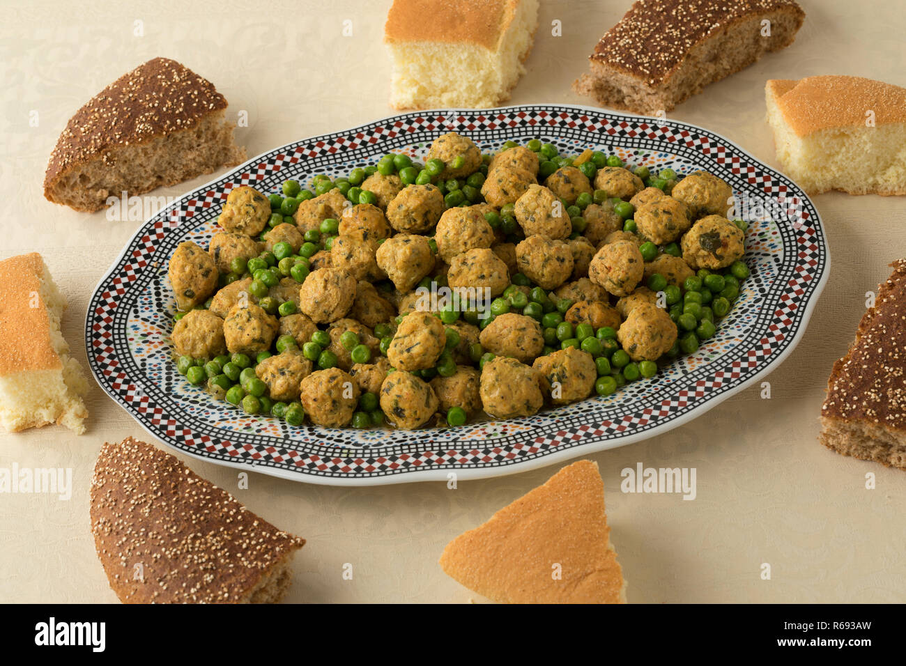 Im marokkanischen Stil Hackfleisch Huhn Kugeln, grüne Erbsen und Brot für das Abendessen Stockfoto