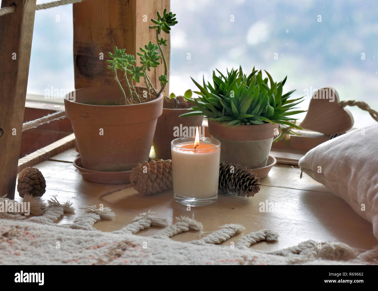 Pflanzen und Kerze vor der Verglasten von Glas in einer Berghütte Stockfoto