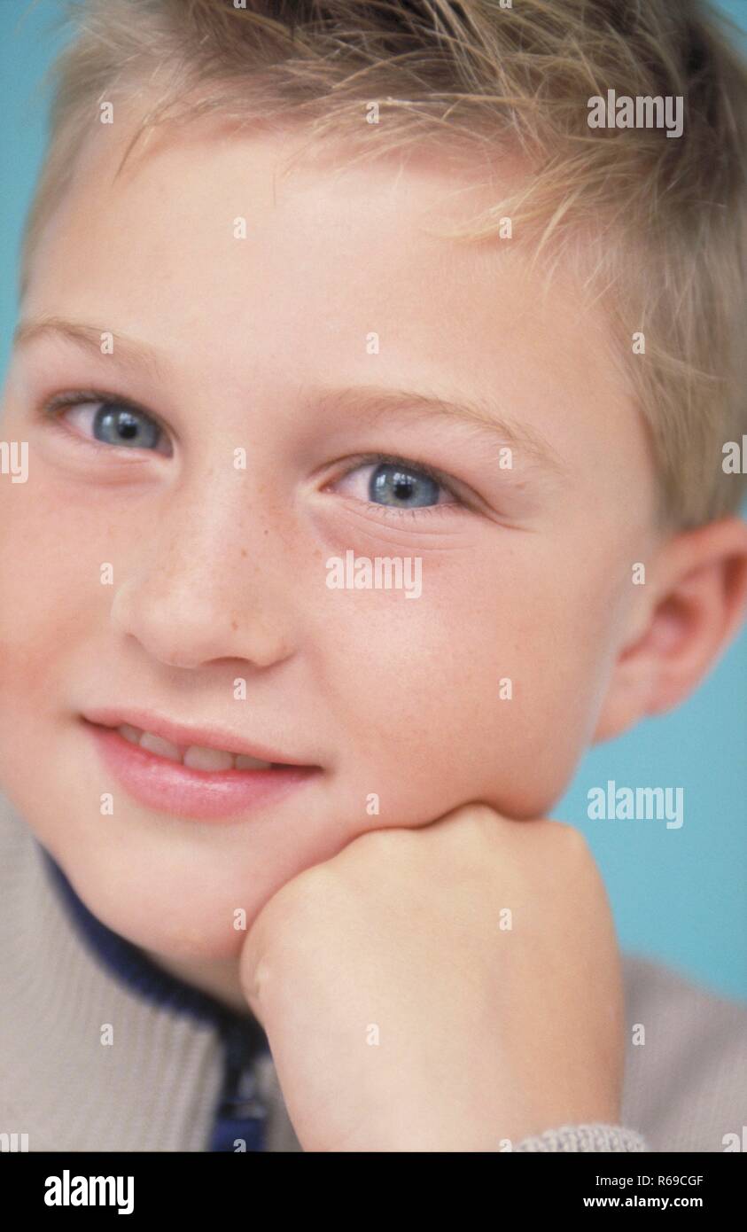 Porträt, Nahaufnahme, dunkelblondr aufgeweckter Junge mit blauen Augen, 9 Jahre, Stuetzt sein Kinn in seine Hand Stockfoto