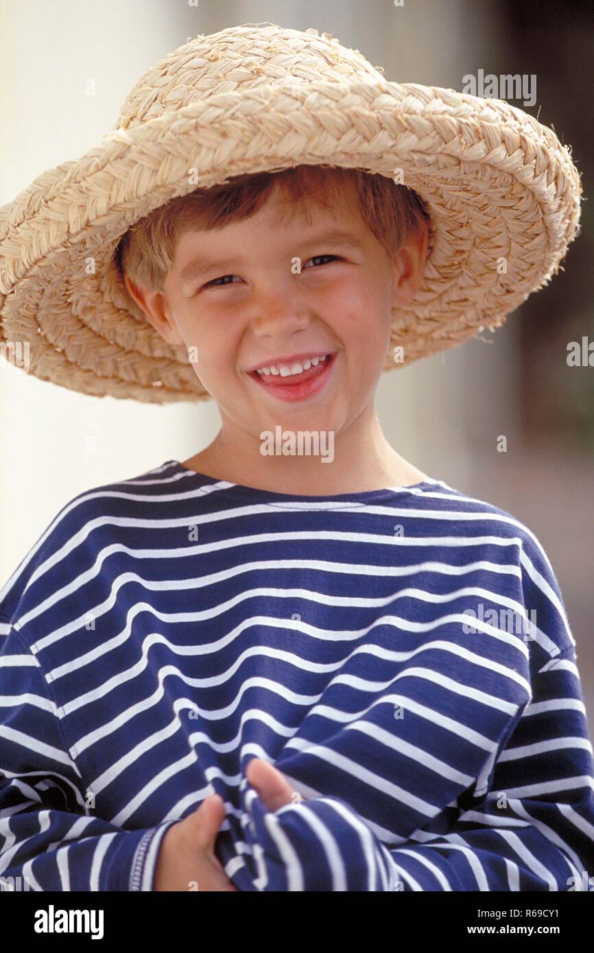 Portrait, Outdoor, blonder verlegen lachender Junge, 6 Jahre alt, bekleidet mit blau-weiss gestreiftem T-Shirt Stockfoto