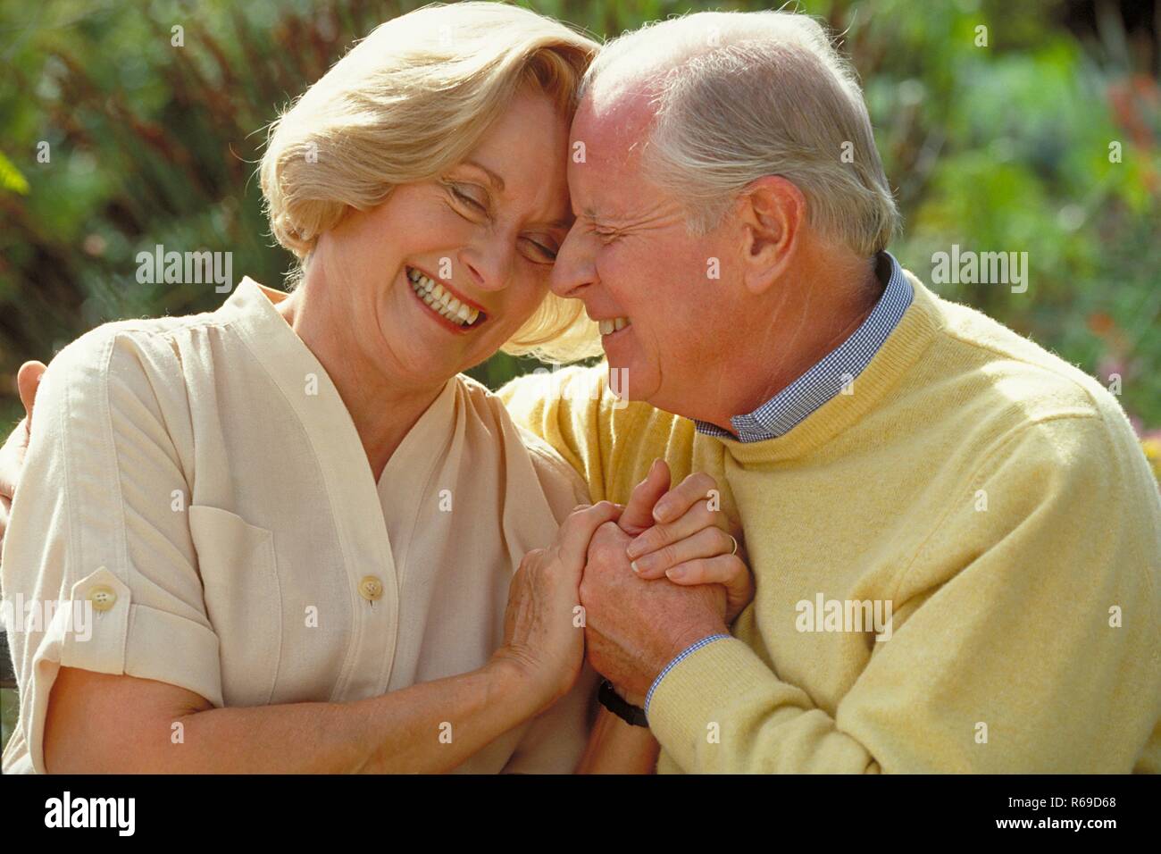 Outdoor, Portrait, Haendchen haltendes lachendes Seniorenpaar bekleidet mit heller Kleidung Stockfoto