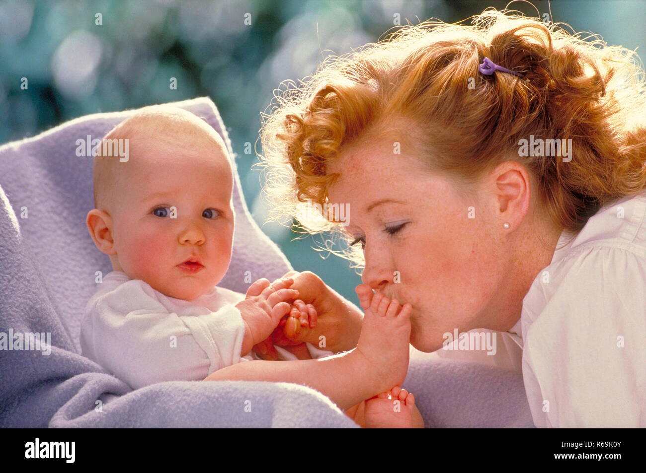 Portrat Nahaufnahme Sommersprossige Frau Mit Rot Gelocktem Haar Nackten Fuesse Kuesst Zaertlich Sterben Ihres Babys Dasauf Einer Flieder Farbenen Decke In Seinem Kindersitz Sitzt Stockfotografie Alamy