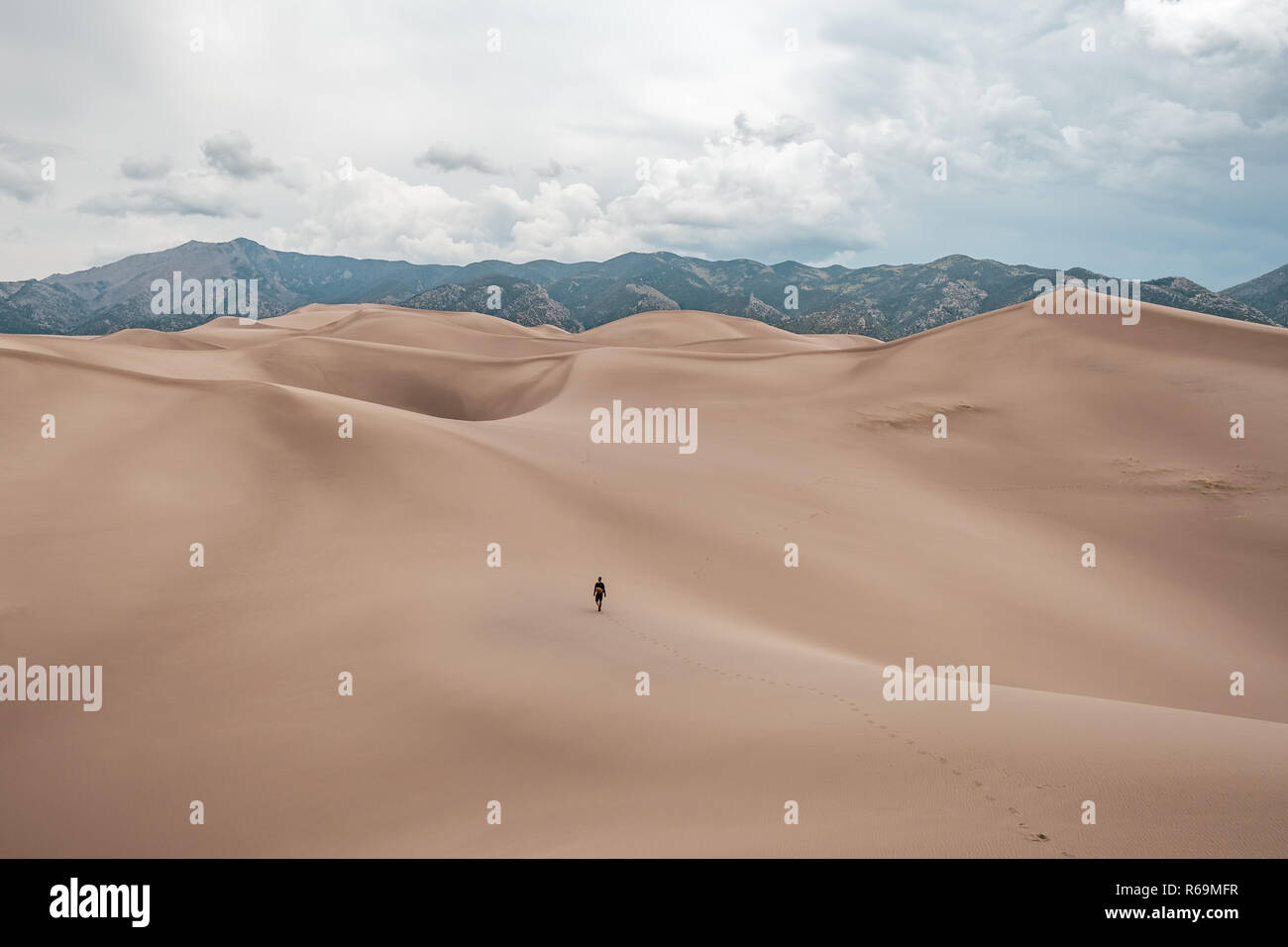 Ein Mann, der riesigen Sanddünen bei stürmischem Wetter an der Great Sand Dunes National Park in Colorado, USA Stockfoto