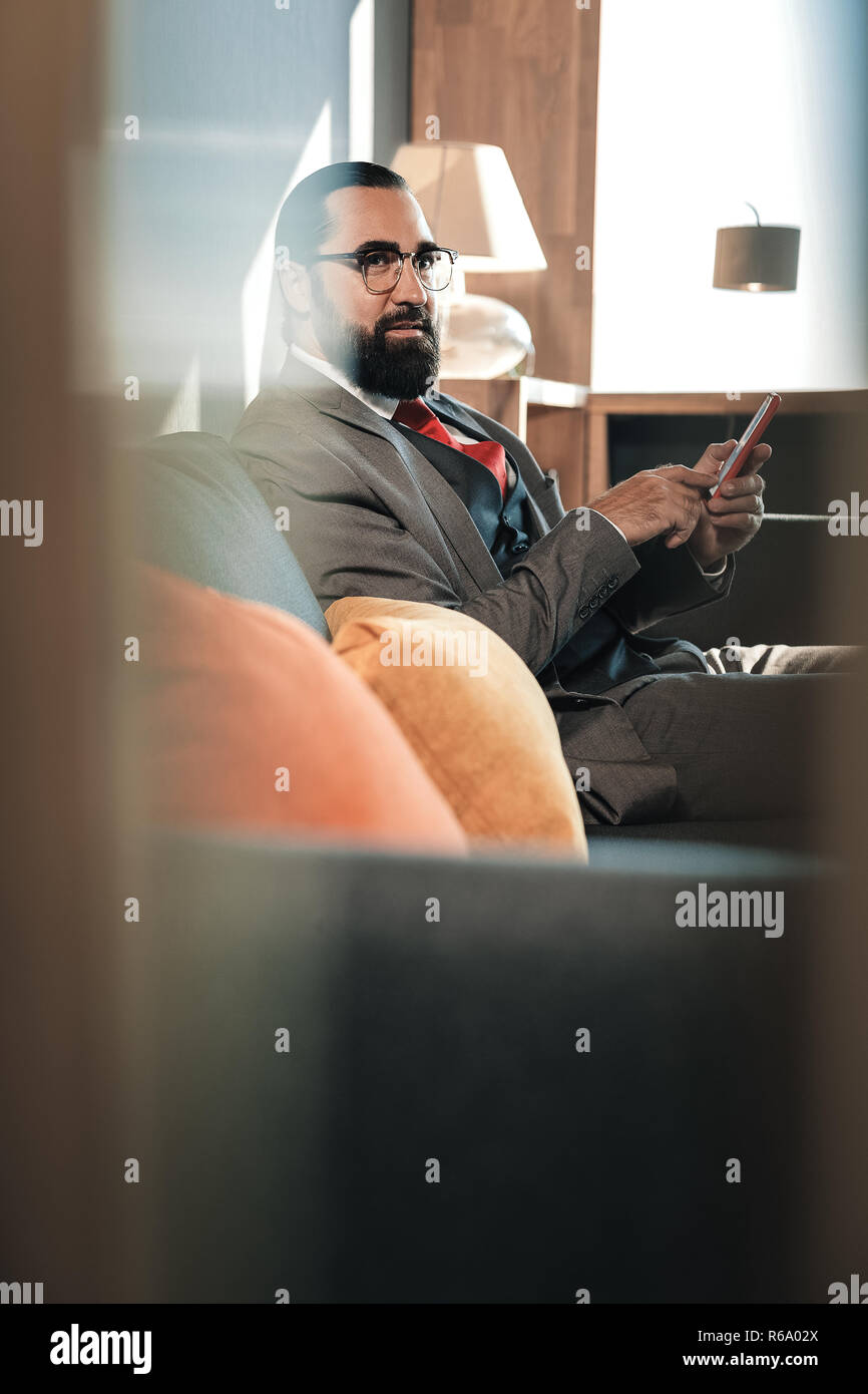 Bärtige Geschäftsmann sitzen auf Grau orange Sofa mit Kissen Stockfoto