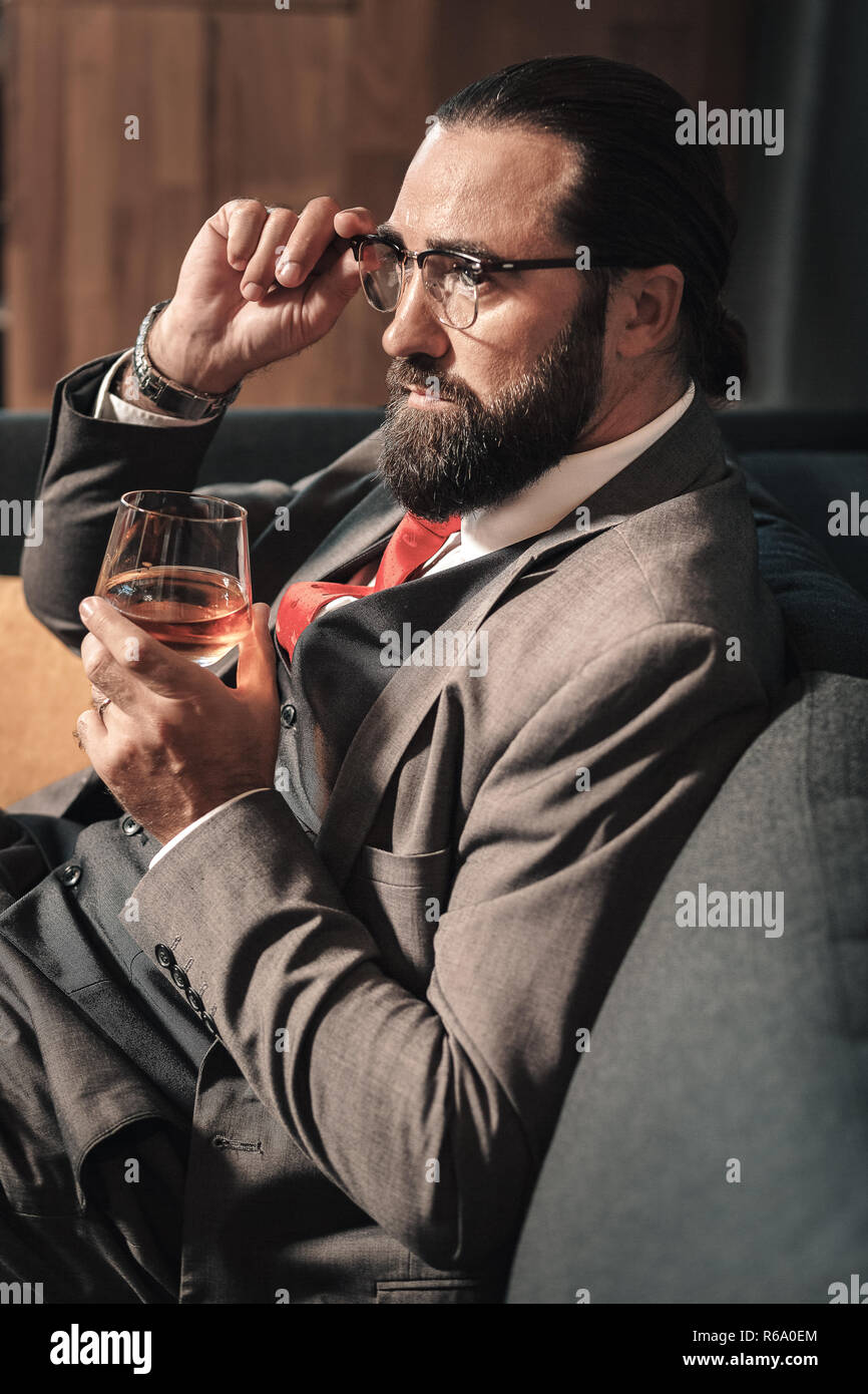 Bärtige Geschäftsmann tragen rote Krawatte trinken einige Cognac Stockfoto