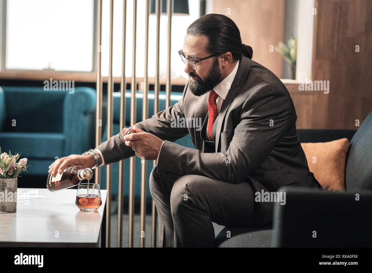 Reifer mann Brille trinken Cognac nach einem harten Arbeitstag Stockfoto