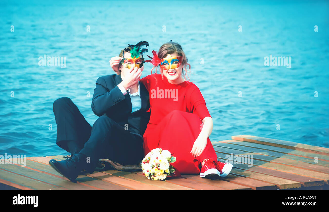 Glückliches Paar in der Maskerade Masken gegen einen türkisfarbenen See Stockfoto