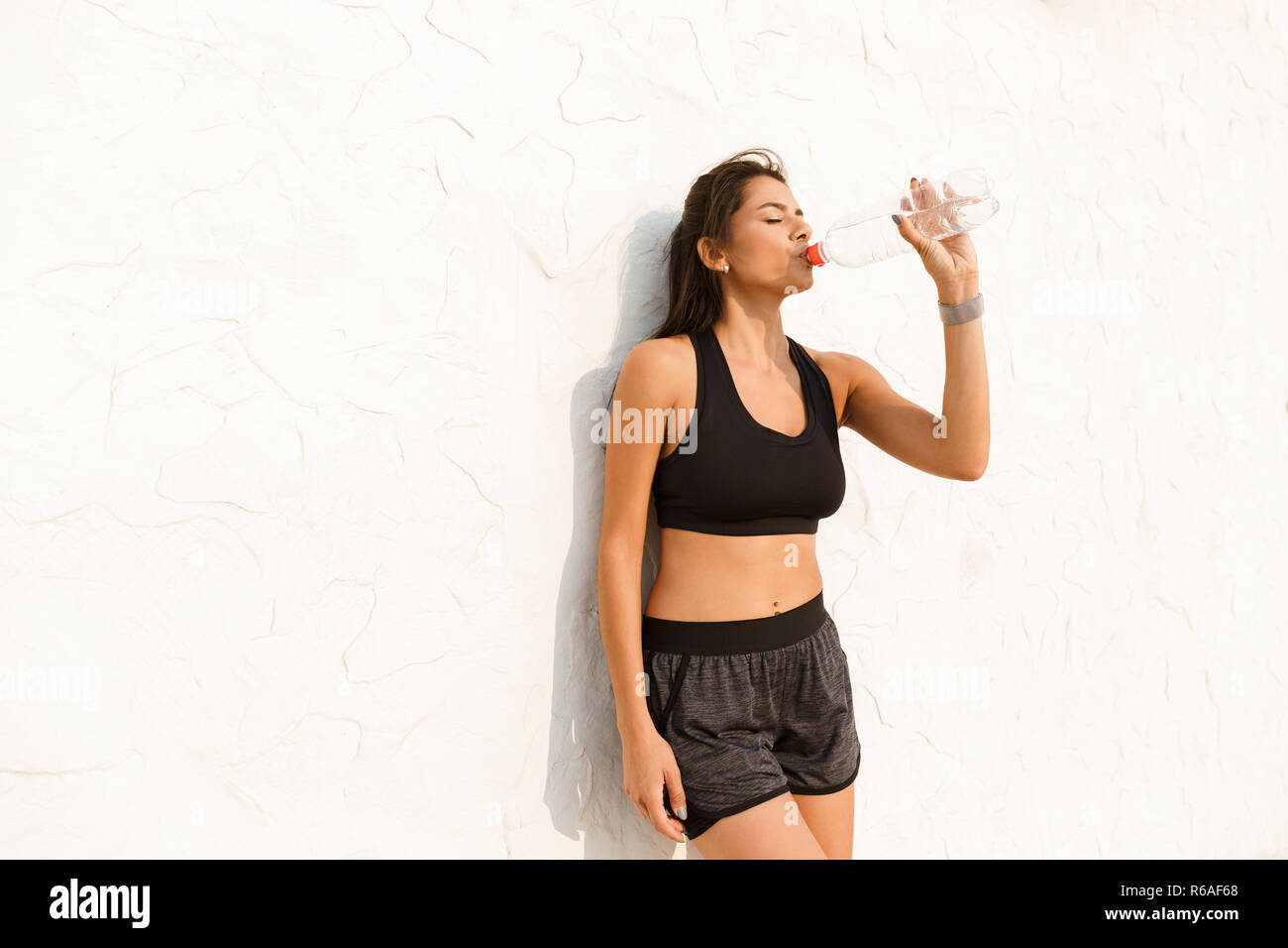 Volle Länge Bild der schönen Frau 20 s Trinkwasser und stehen über Wall nach Morgen Workout Stockfoto