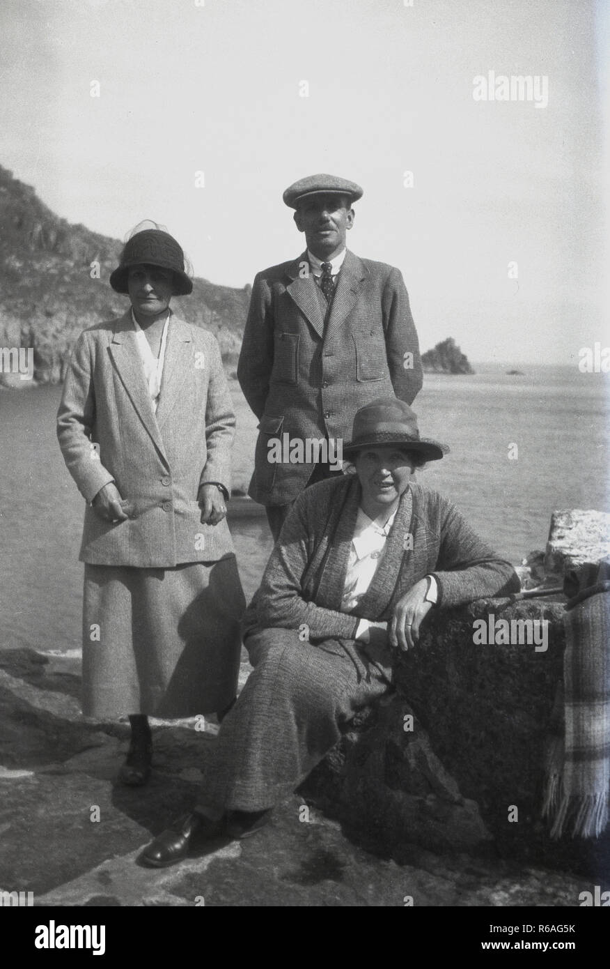1920 s, historischen, ein Mann und zwei Damen für ein Foto posieren am Meer das Tragen von Kleidung und Hüte der Ära, England, UK. Stockfoto