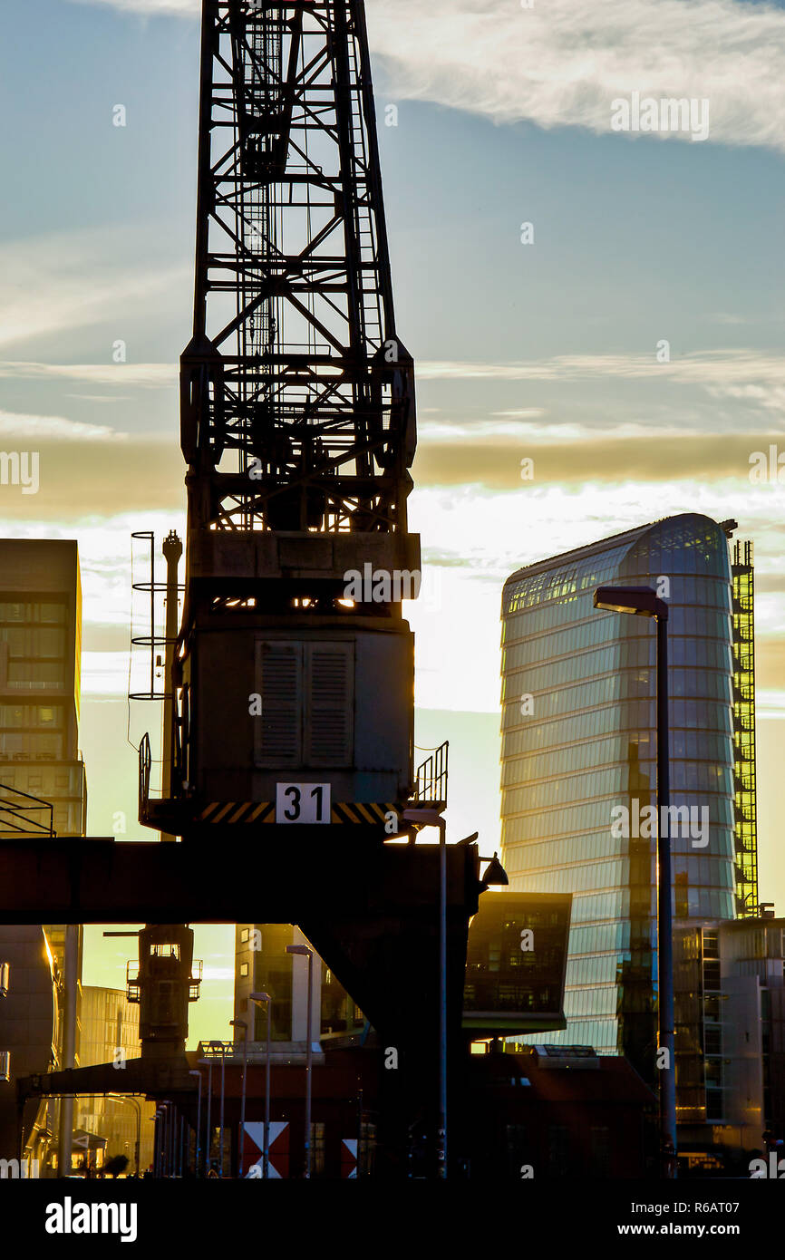 Gegenlichtaufnahme im Medienhafen Düsseldorf im Vordergrund ein Hafenkran und im Hintergrund das Bürogebäude ANMELDEN! Vom Architekten Helmut Jahn, 2015. Hintergrundbeleuchtung Schuß im Medienhafen Düsseldorf im Vordergrund ein Hafen mit Kran und im Hintergrund das Bürogebäude ANMELDEN! Der von dem Architekten Helmut Jahn, 2015. Stockfoto