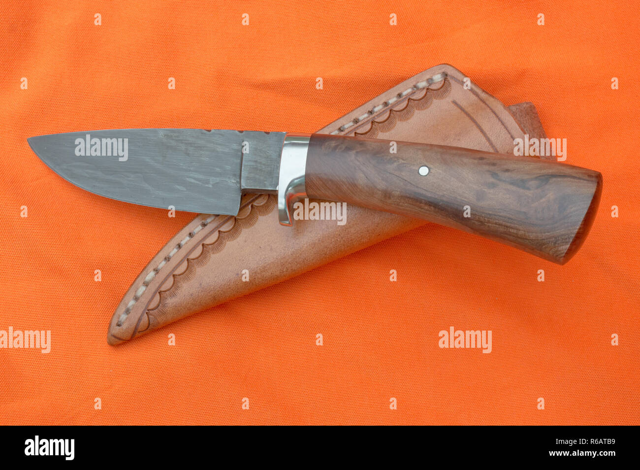 Ein Damaskus skinner Messer und Scheide sind oben auf einem hellen orange  Hintergrund Stoff angezeigt Stockfotografie - Alamy