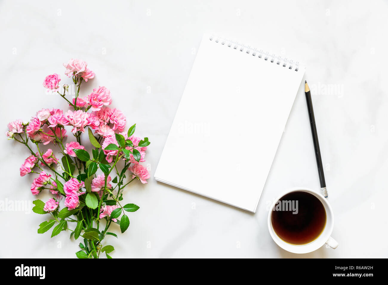 Rosa Blumen Blumenstrauß, Kaffeetasse und leeres Papier notebook Ihr Text auf weißem Hintergrund zu setzen. Mock up. Flach. top anzeigen. Urlaub conce Stockfoto
