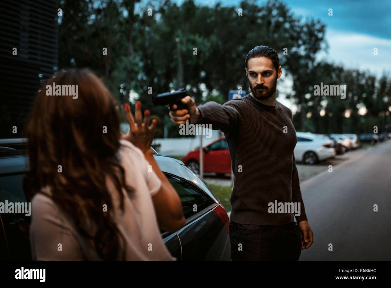 Bandit Raubüberfälle Frau mit Pistole und sie ist Gefühl schockiert und stehend mit dem Auto erschrocken. Stockfoto