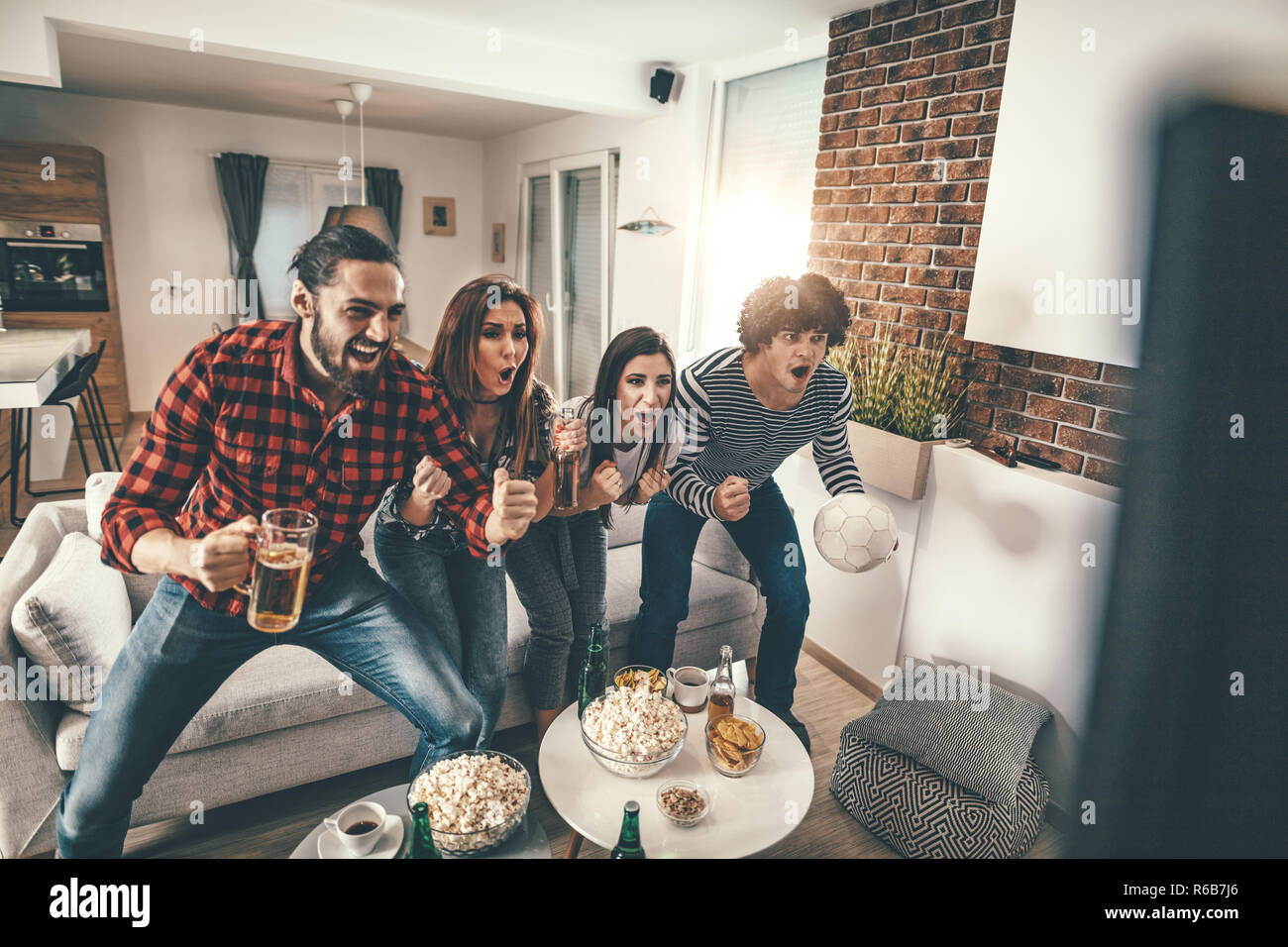 Freunde sind Fans von Sport Spiele wie Fußball lieben ihre Freizeit zu Hause zusammen. Sie sind Schreiend und gestikulierend für einen Sieg. Stockfoto