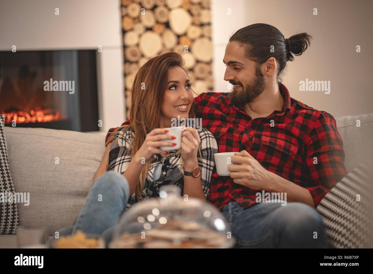 Nett schön Paar ist Tee trinken zu Hause auf dem Sofa sitzen. Sie haben ein tolles Wochenende in Nizza Unternehmen im Innenbereich. Stockfoto