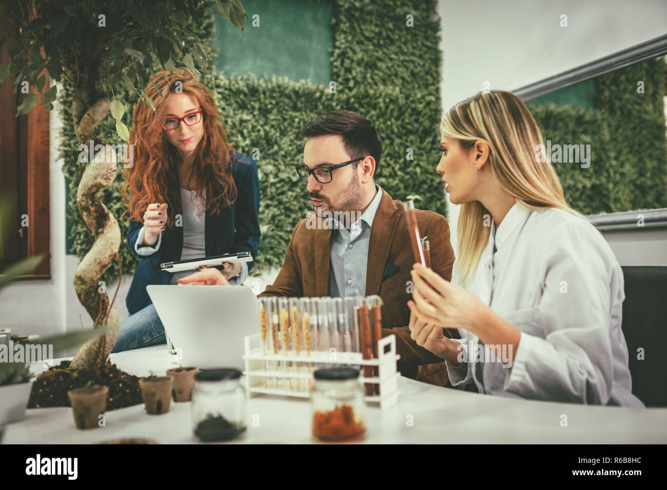 Clevere progressive junge Ingenieure arbeiten an digitalen Tablet auf einer ökologischen Bauvorhaben im Büro, reden über einige grüne Projekt. Stockfoto