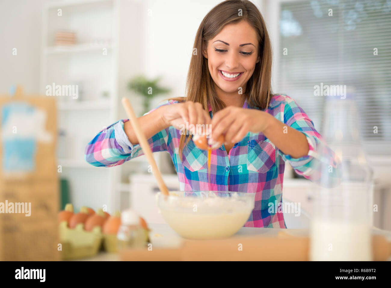 Schöne junge Frau Eier in der heimischen Küche zu brechen. Stockfoto