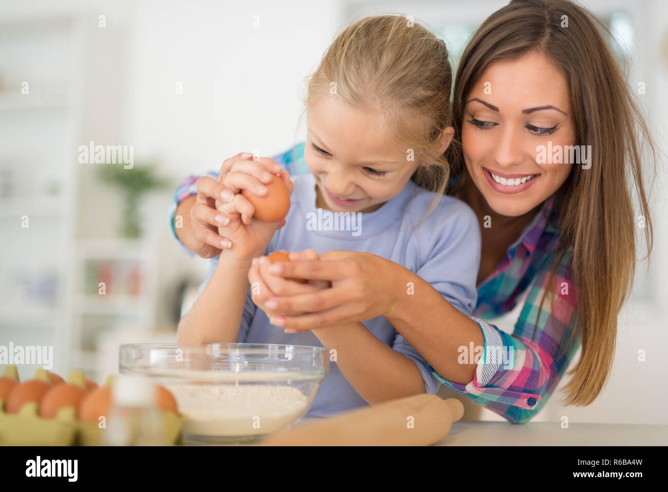 Schönen Mutter und ihrer Tochter, die Eier gemeinsam in der heimischen Küche. Stockfoto