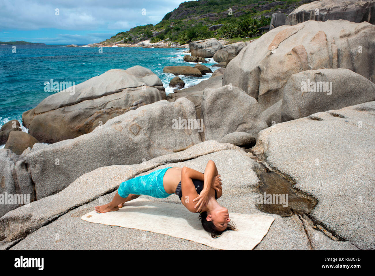 Yoga auf Felsen in sechs Richtungen Zil Pasyon Luxus Hotel. Felicite Island Seychellen. Stockfoto