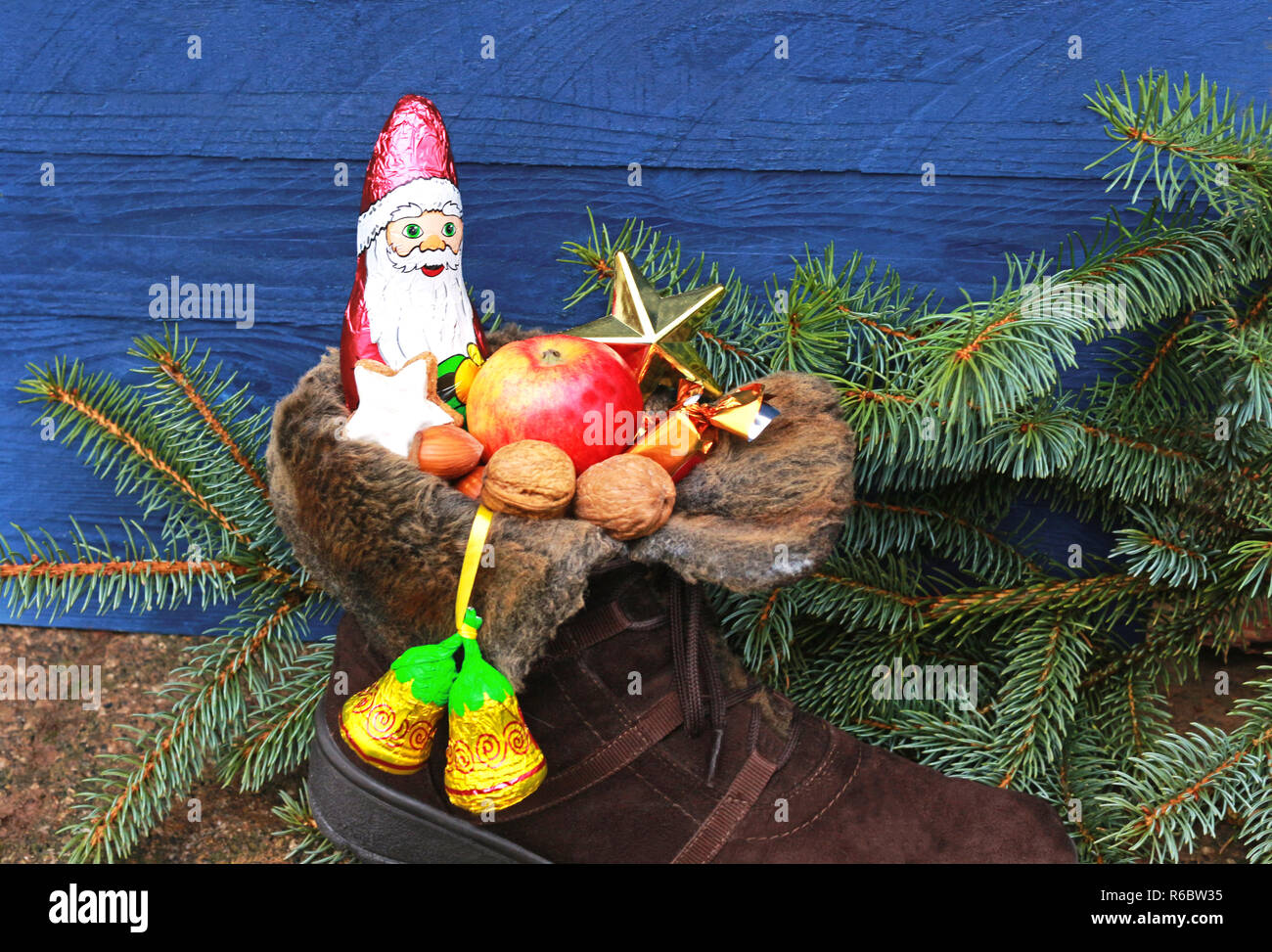 Weihnachtsstrumpf mit Schokolade Santa und Muttern vor Niederlassungen und einem blauen Hintergrund holz fichte Stockfoto