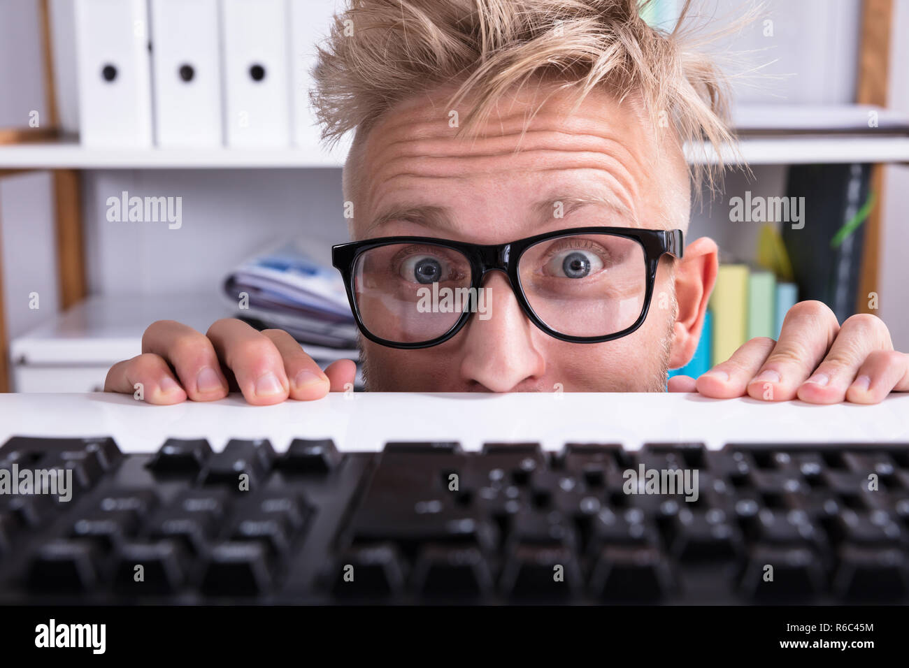 Lustige Geschäftsmann tragen Brillen versteckt sich hinter dem Schreibtisch  im Büro Stockfotografie - Alamy
