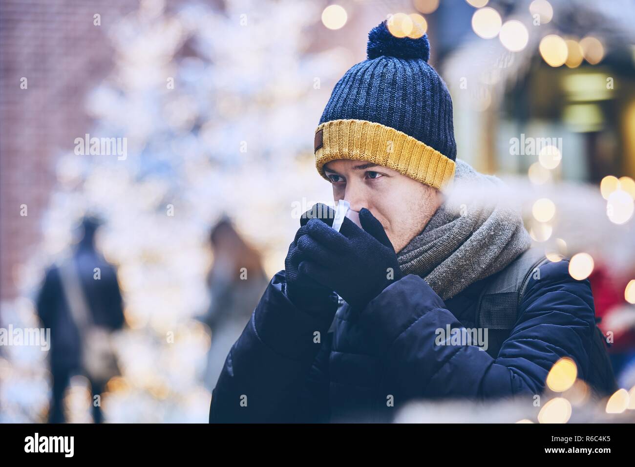 Junger Mann trinken Glühwein. gegen Beleuchtete Weihnachtsbäume. München, Deutschland. Stockfoto