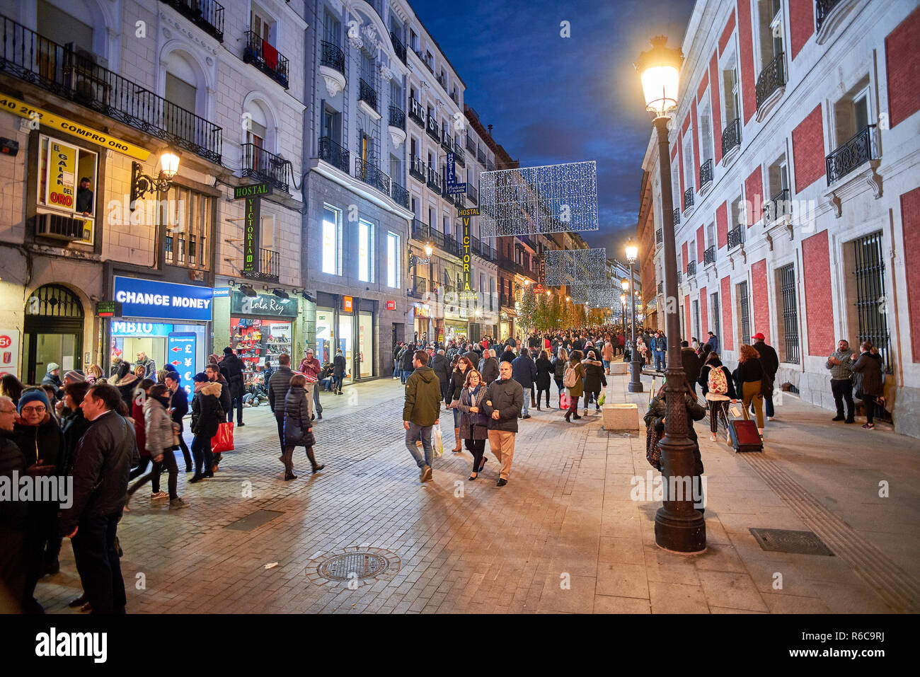 Menschen zu Fuß auf die Calle Carretas Straße bei Einbruch der Dunkelheit durch die Weihnachtsbeleuchtung illuminiert. Blick von der Puerta del Sol. Stockfoto