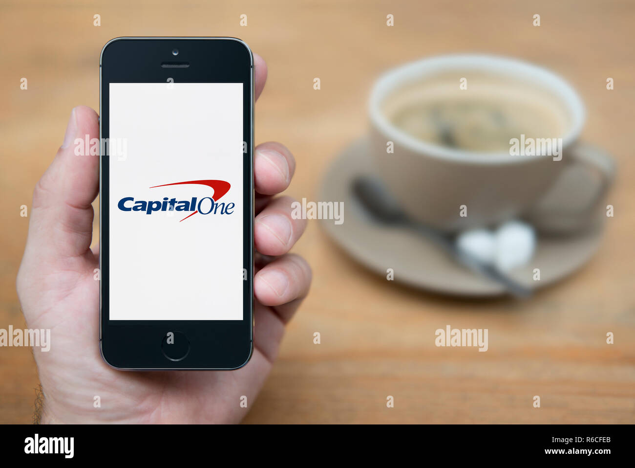 Ein Mann schaut auf seinem iPhone die zeigt die CapitalOne Logo (nur redaktionelle Nutzung). Stockfoto