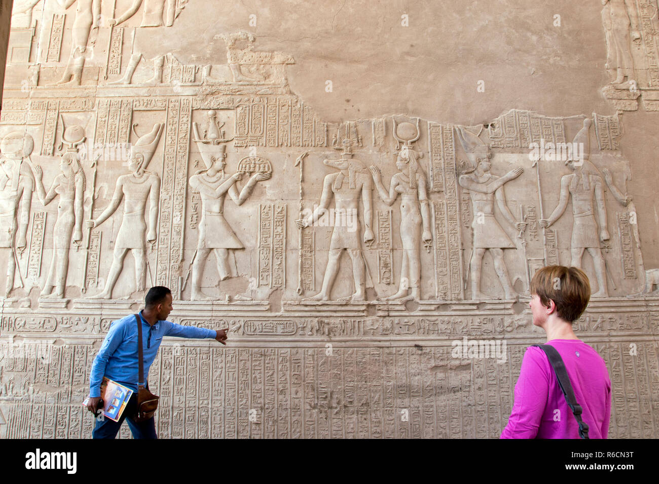 Ein Reiseleiter erklärt die bas-relief Schnitzereien an eine Besucherin am Tempel von Kom Ombo, in Kom Ombo, Ägypten. Stockfoto