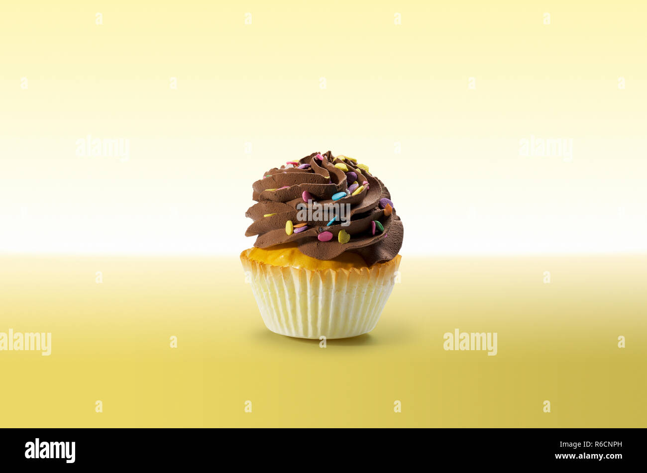 Cupcake mit Schokolade Zuckerguss auf gelbem Untergrund Stockfoto