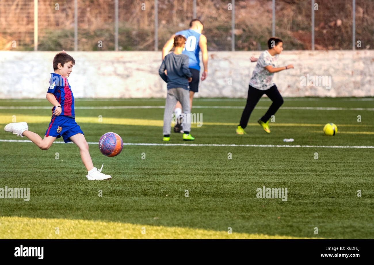 Hydra, Griechenland - 4. Oktober 2018: Ein Kind spielen Fußball in ein Fußballfeld mit der Barcelona Shirt in Hydra, Griechenland. Stockfoto