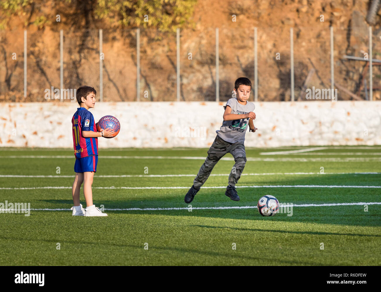 Hydra, Griechenland - 4. Oktober 2018: Zwei Kinder spielen Fußball in ein Fußballfeld eine von Ihnen mit der Barcelona shirt iin Hydra, Griechenland. Stockfoto
