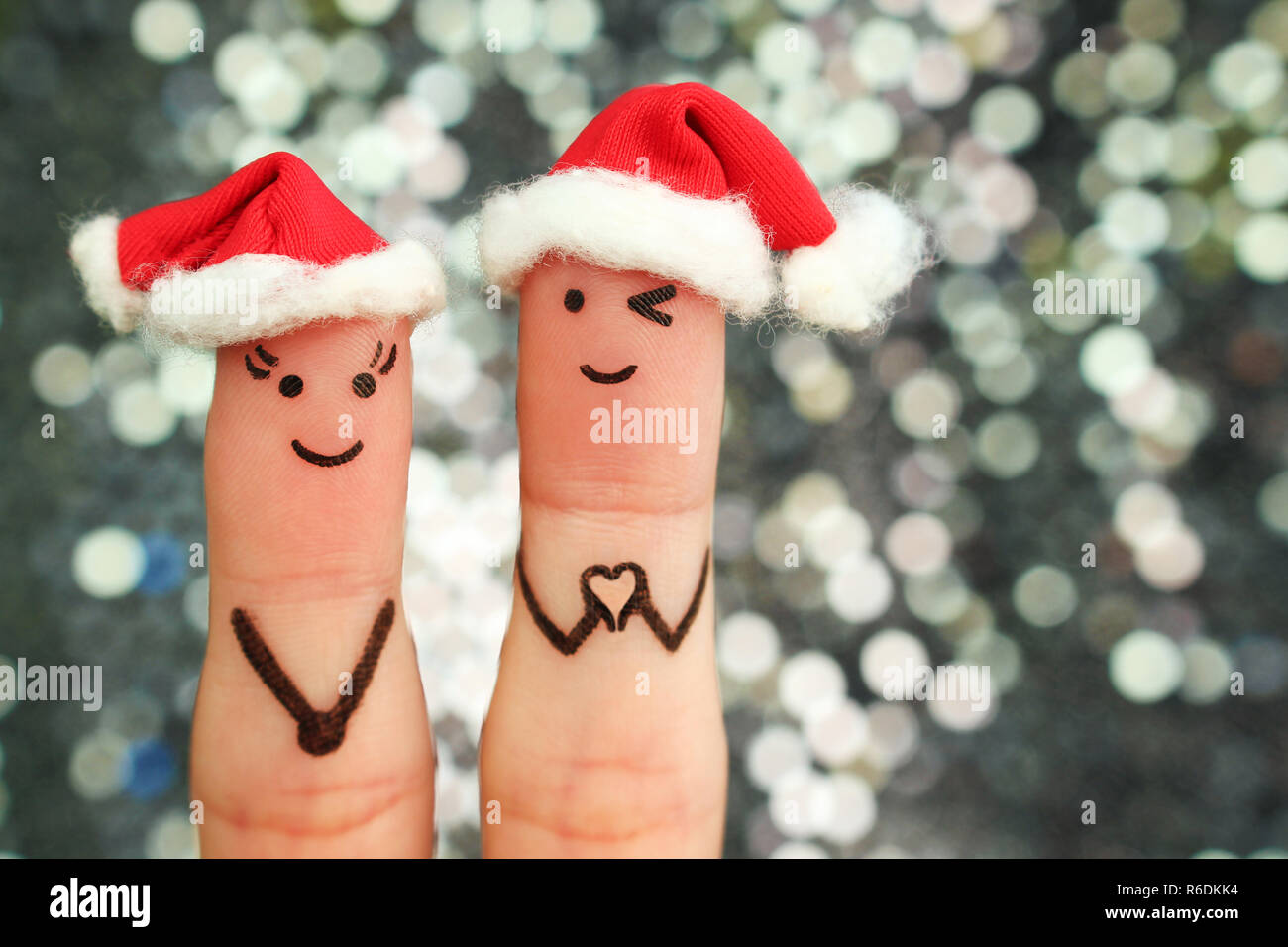 Finger Kunst der Paar feiert Weihnachten. Konzept von Mann und Frau lachend im neuen Jahr Hüte. Freund, Finger in Herzform. Stockfoto