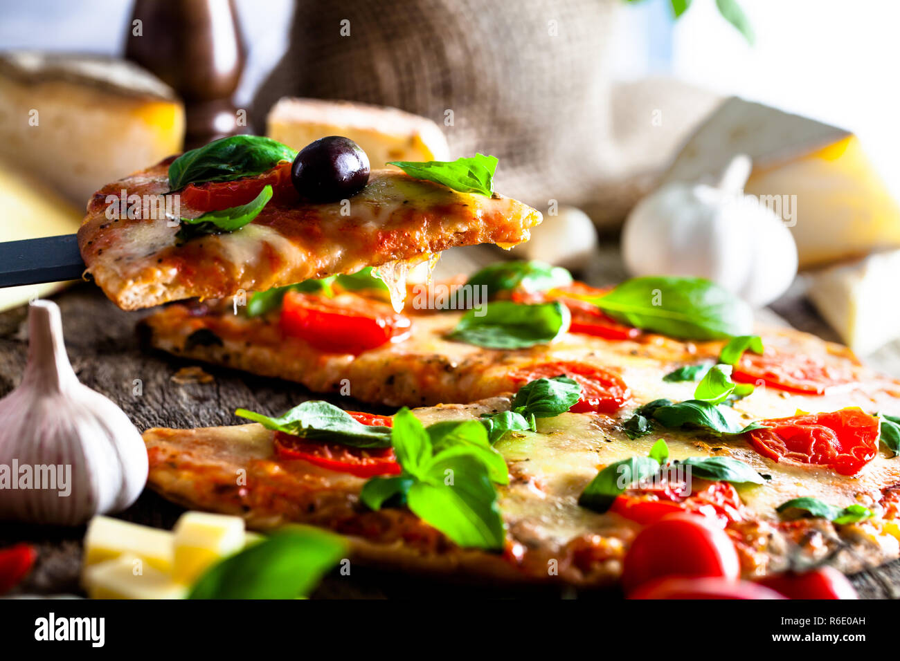 Pizza auf Holz mit Zutaten. Pizza mit Käse, Tomaten und Basilikum. Rustikale italienische Pizza Stockfoto