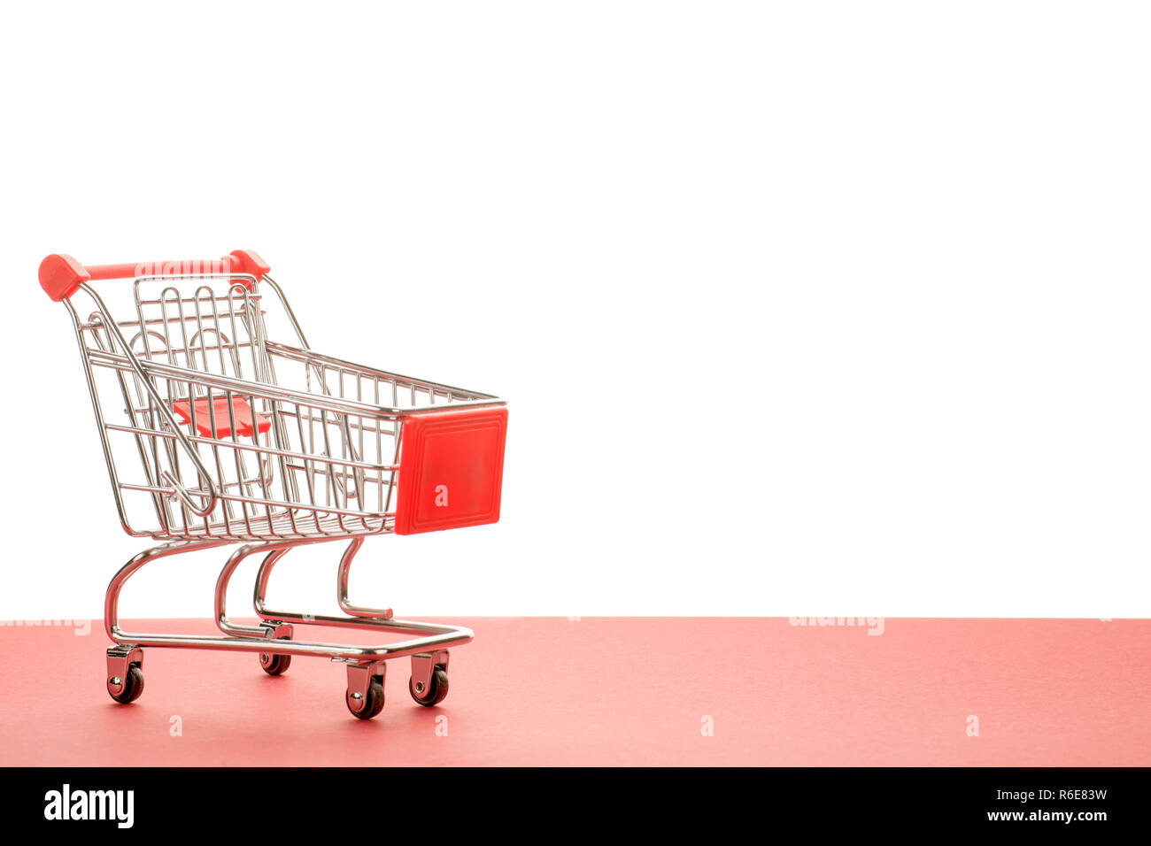 Kleine leer Warenkorb mit rotem Griff. Zu den roten und weißen Hintergrund mit Kopie Raum Stockfoto