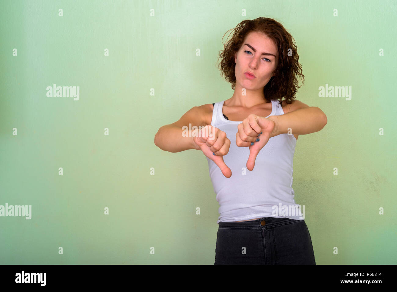 Studio schoss der schönen Jugendmädchen geben Daumen nach unten gegen Stockfoto