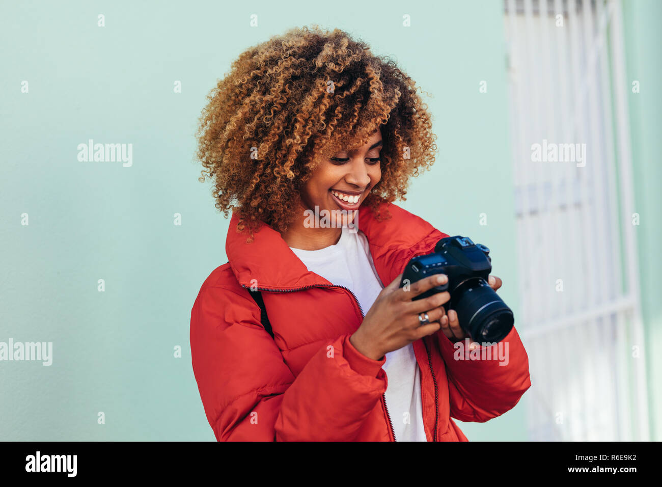 Fröhliche afro-amerikanische Frau im Urlaub die Fotos stehen im Freien. Porträt einer Frau, die an Ihrer DSLR-Kamera auf der Suche nach einem Foto. Stockfoto