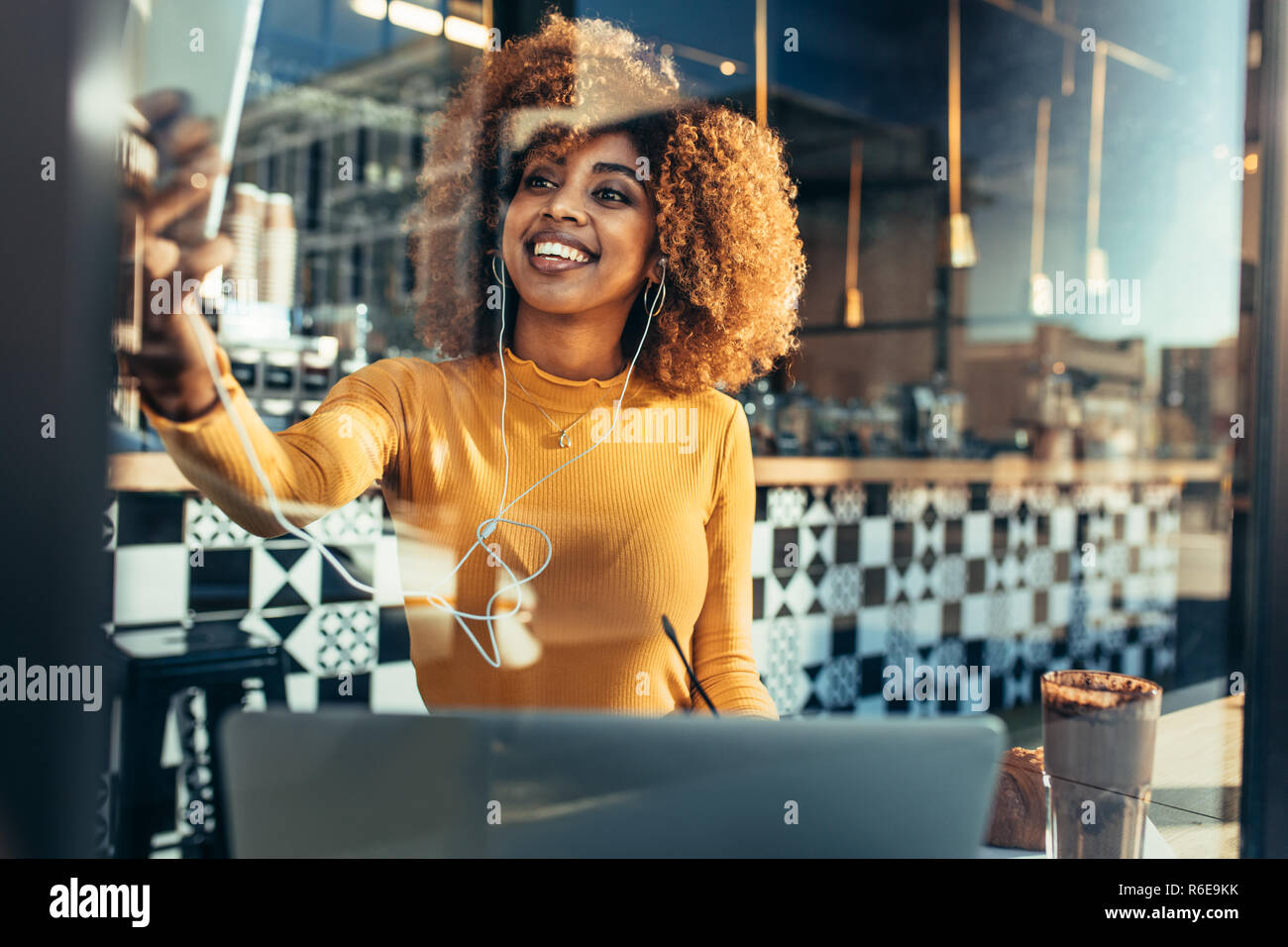 Frau freier Mitarbeiter sitzen in einem Café einen selfie auf Handy mit Laptop vor. Lächelnd afro-amerikanische Frau, eine Videokonferenz auf Mobi Stockfoto