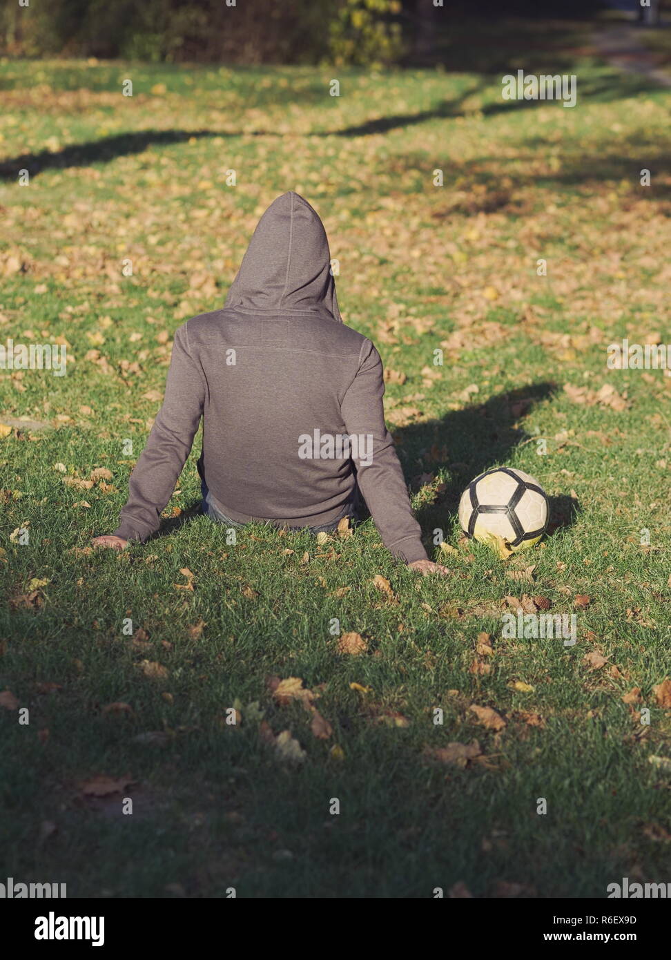 Fußball-Spieler posiert mit Fußball im Park an einem sonnigen Herbsttag Stockfoto